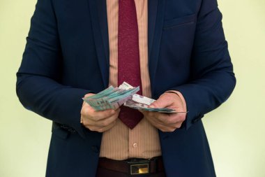 Takım elbiseli bir adam büyük miktarda Ukrayna parası tutuyor ve gelirini gösteriyor. - Evet. Yeni banknotlar 1000 ve 500 Hryvnia