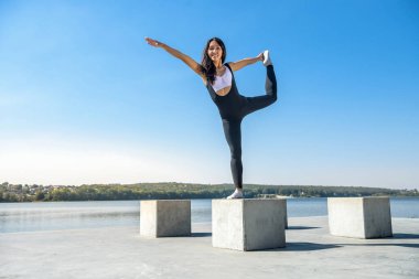 Güzel genç bir kadın sabah parkta çalışmadan önce esneme egzersizi yapıyor.