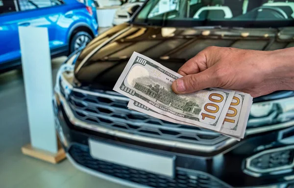 在汽车房里买汽车时 男性的手显示出一美元 — 图库照片