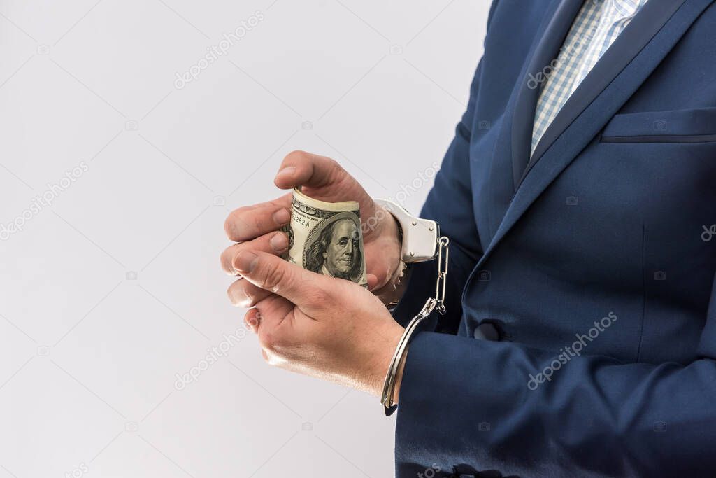 Bribe and corruption areest man who hold dollar in hand cuff, isolated. Crime