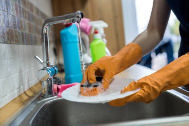 Eldivenli bir kadın mutfakta bulaşık yıkıyor. ev işleri