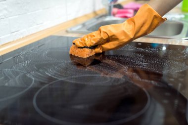  Kadın el temizliği sünger ve deterjan ile modern cam elektrikli hob.