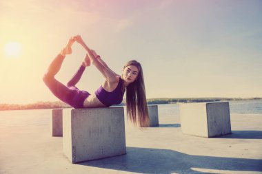 Güzel genç bir kadın sabah parkta çalışmadan önce esneme egzersizi yapıyor.