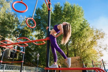 Güzel genç bir bayan oyun parkının caddesinde egzersiz yapıyor. İyi fiziksel biçim ve sağlıklı yaşam tarzı kavramı