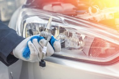 Adam yeni modern halojen otomobil ampulünü tamir için tutuyor. otomotiv ekipmanı