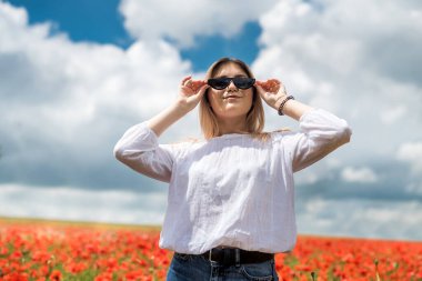 Haşhaş tarlasında beyaz bluzlu Ukraynalı genç bayan. yaz zamanı