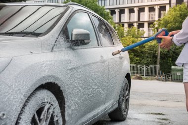 Köpüklü su tabancası olan Ukraynalı bir kadın arabasını temizliyor. temizlik kavramı