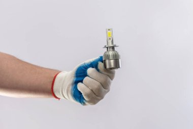 Eldiven içinde insan eli, yeni halojen araba ampulleri tutuyor, izole edilmiş. Otomobil farları için lamba