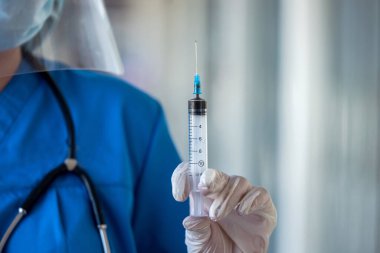 Klinikte elinde şırınga tutan üniformalı kadın doktor. Tıbbi konsept