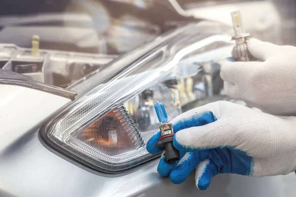 Installing replacement new modern halogen led car headlight bulb. mechanic hold auto lamp