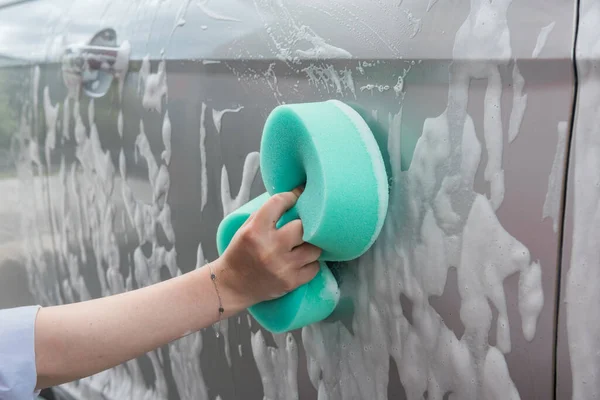 woman washes the car with a sponge and foam. quality car service. concept of cleanliness