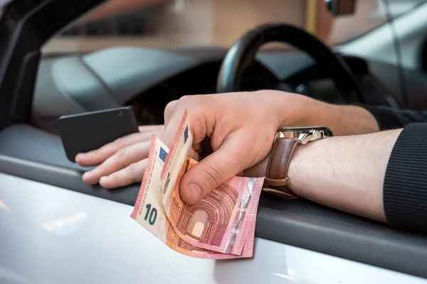 male\'s hand holding euro bills and key inside car for buy or rent. finance