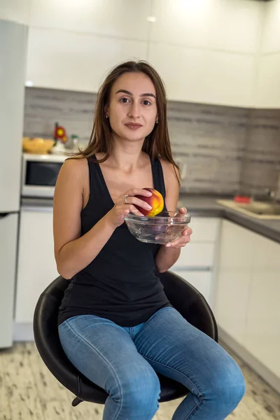 woman in sportswear holding fresh fruits in the kitchen for breakfast. concept of healthy eating