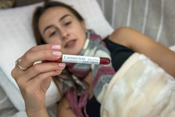 sick woman lies at home on the couch and looks at the whole positive result of the coronavirus