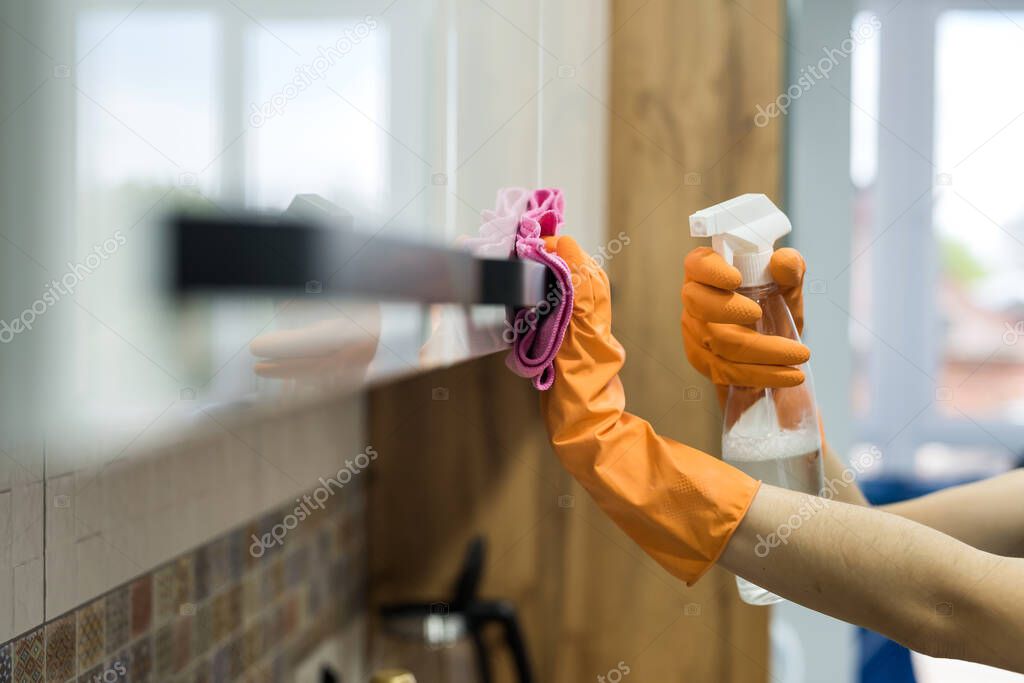 woman in rubber gloves and cleaning the kitchen counter with sponge. housework