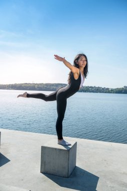 Güzel genç bir kadın sabah parkta çalışmadan önce esneme egzersizi yapıyor.