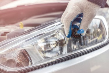Tamirci arabanın farındaki yeni halojen ampulü değiştiriyor. otomotiv endüstrisi