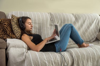 Genç ve zayıf bir kadın rahat koltukta uzanmış tabletine bakıyor. özgürlük