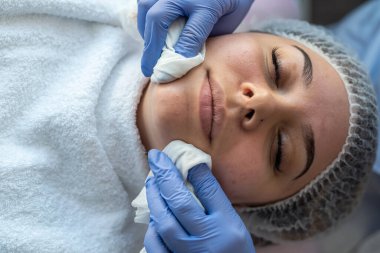 Kozmetik uzmanı, güzellik kliniğinde bir masada yatan genç bir kadının ameliyatına yüz hazırlıyor. Güzellik endüstrisi konsepti