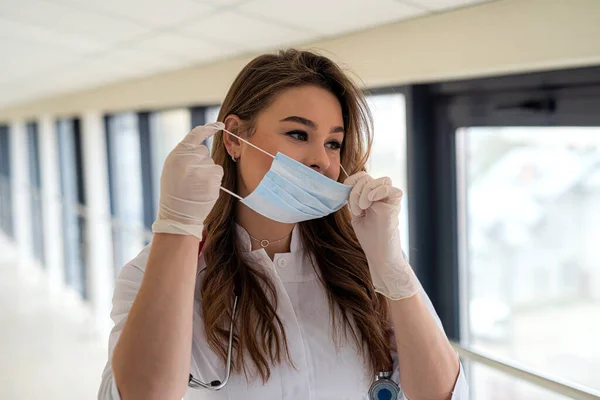 Pretty female doctor putting on face mask. Medical Concept