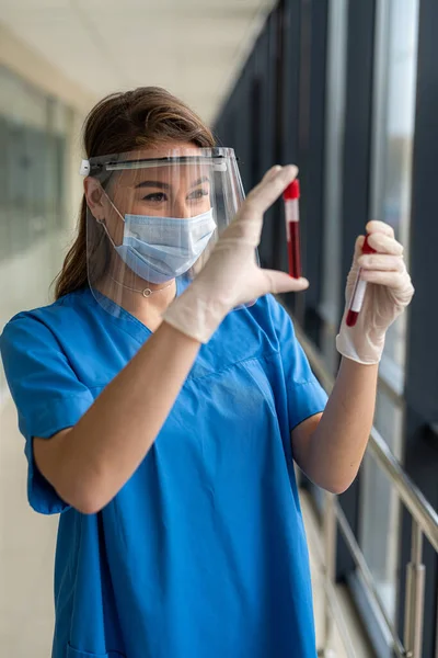 young pretty nurse looking at a blood sample for diagnostic on Coronavirus or COVID-19