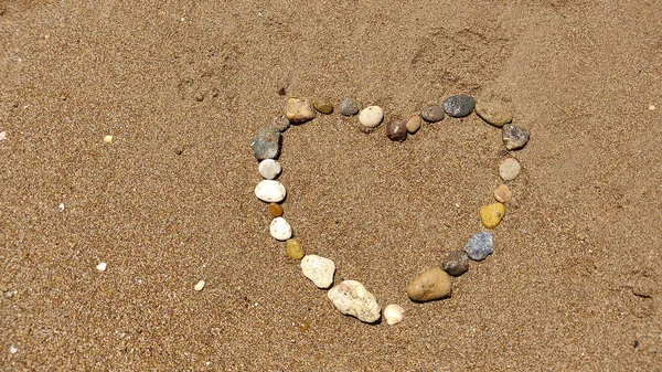 symbol of the heart drawing stones on the sand. Summer vacation