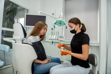 Diş hekimi, diş sağlığı kliniğinde dişlerini nasıl fırçalayacağını gösteriyor. Sağlık hizmetleri