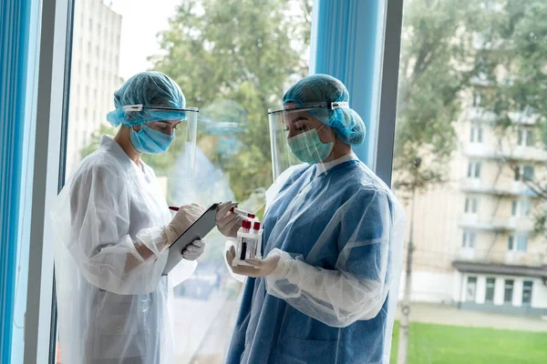 two young interns work with test tubes with blood for laboratory research to detect a new dangerous virus COVID-19