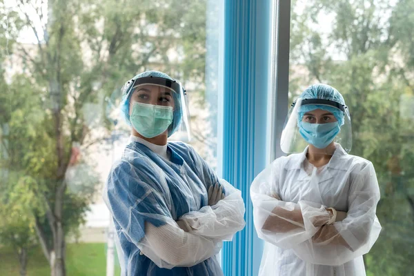 two female intern doctor in corridor of modern clinic in protective clothing during coronavirus pandemic