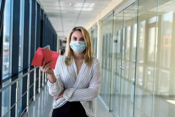 charming young lady in a medical mask holding an envelope with money in the mall. finance concept