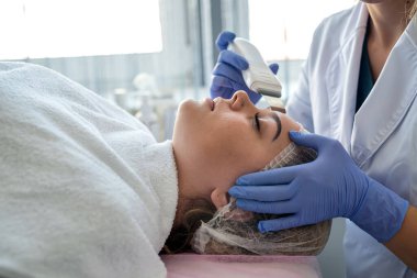 Doktor güzellik salonunda yüz bakımını ultrasonik olarak yapıyor. Profesyonel cilt bakımı