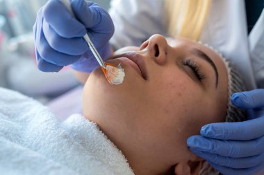 Mavi eldivenli eller cilt bakımı için hastanın yüzüne beyaz nemlendirici krem sürerler. Temiz ve yumuşak vücut derisi kavramı