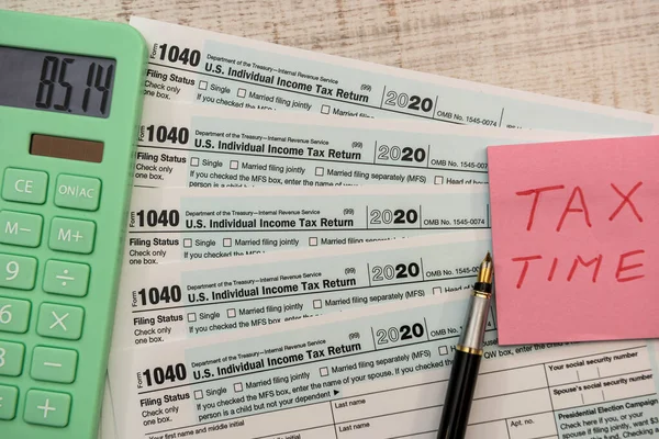 text tax time on sticker with calculator on 1040 tax form 2020 2021