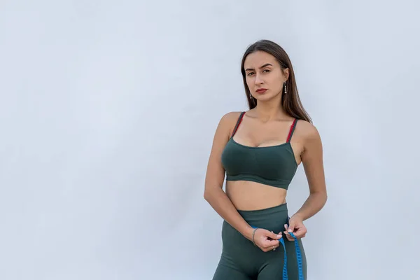 緑色のスポーツウェアの可愛いスリムな女の子は センチメートルのテープで腰を測定します 健康と食事の概念 — ストック写真