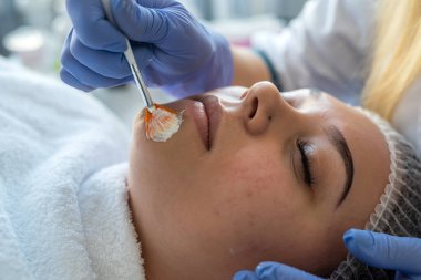 Güzellik kliniğinde kadın müşterinin cildine şifa kremi sürüyor. Sağlık hizmetleri