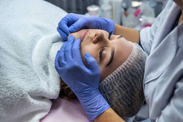 Mani Cosmetologo Guanti Azzurri Toccano Faccia Paziente Giovane Che Massaggio — Foto Stock