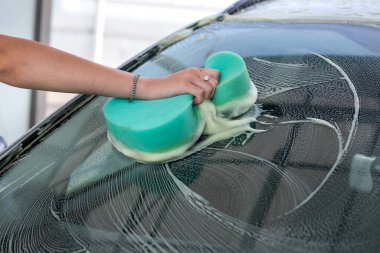 Yakından bakınca köpüklü yıkamalı yeşil sünger kullanılıyor. temizlik kavramı.