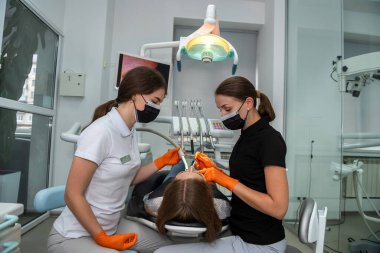  Kadın dişçi, dişçi muayenesi için hazırlanıyor genç bayan hasta. Sağlıklı dişler