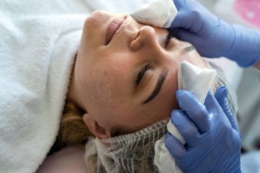 Kozmetik uzmanı, güzellik kliniğinde bir masada yatan genç bir kadının ameliyatına yüz hazırlıyor. Güzellik endüstrisi konsepti