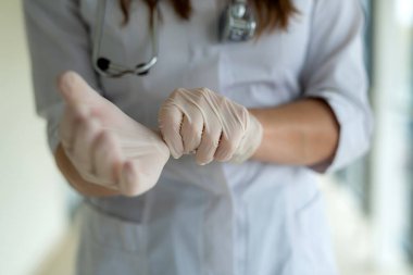 Beyaz üniformalı kadın doktor güvenlik için lastik eldiven giyer. Covid 19 salgını kavramı