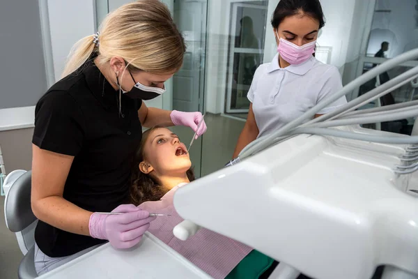 female dentist preparing for dental exam young woman patient. Healthy teeth
