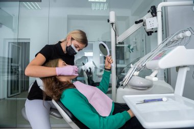 Dişçi klinikteki hastanın ağız boşluğunu inceliyor. tıbbi konsept