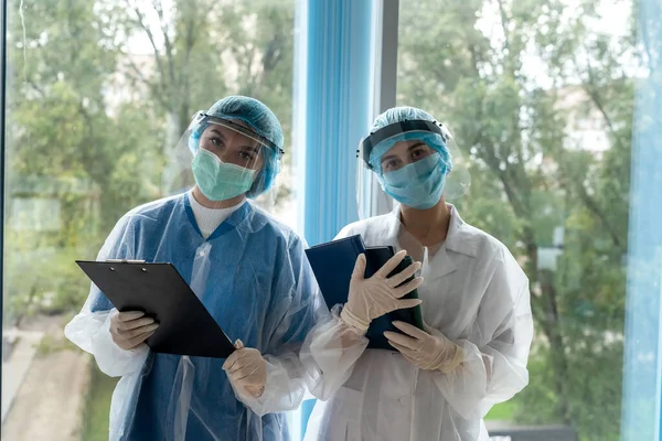two female intern doctor in corridor of modern clinic in protective clothing during coronavirus pandemic
