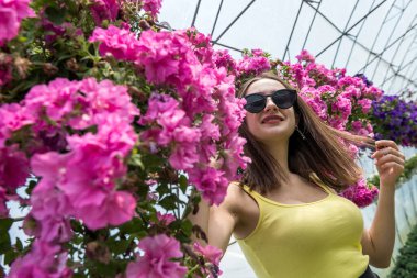 Çiçek serasında kameraya poz veren güzel genç bir kadın. Güzellik