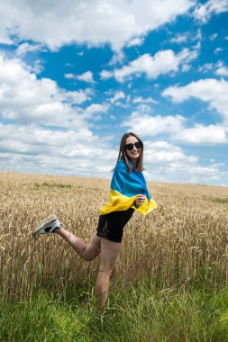 Buğday tarlasında sarı-mavi Ukrayna bayrağıyla oldukça zayıf bir kız. Yaşam biçimi