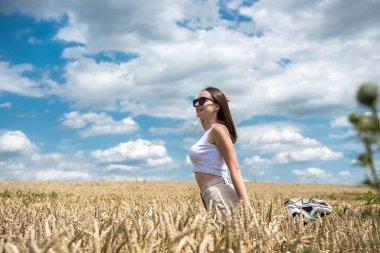 Buğday tarlasında duran gülümseyen genç kadının portresi. Özgür mutlu kız