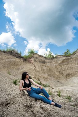 Günlük kıyafetli genç bayan yaz vakti kum kayalıklarında rahatla.