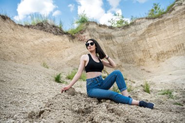 Güzel kadın taş ocağında kumda oturuyor. Yaz tatilinin tadını çıkar.