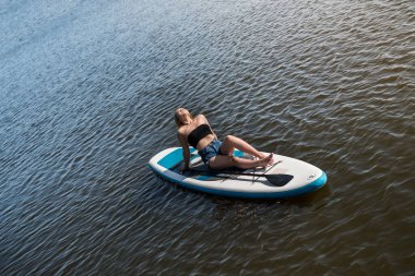  Yazın güzel bir kız suda yemek masasında dinleniyor. Aktif yaşam tarzı kavramı. 