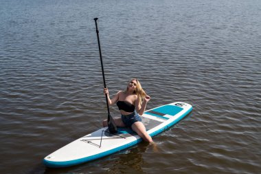 Genç bayan sörfçü yemek masasında uzanıyor ve doğada dinleniyor, yaz zamanı özgürlük.